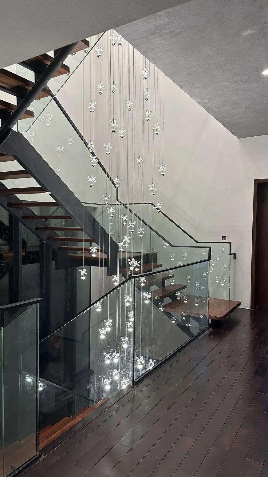 The crystal light illuminating the glass balustrade and wood steps