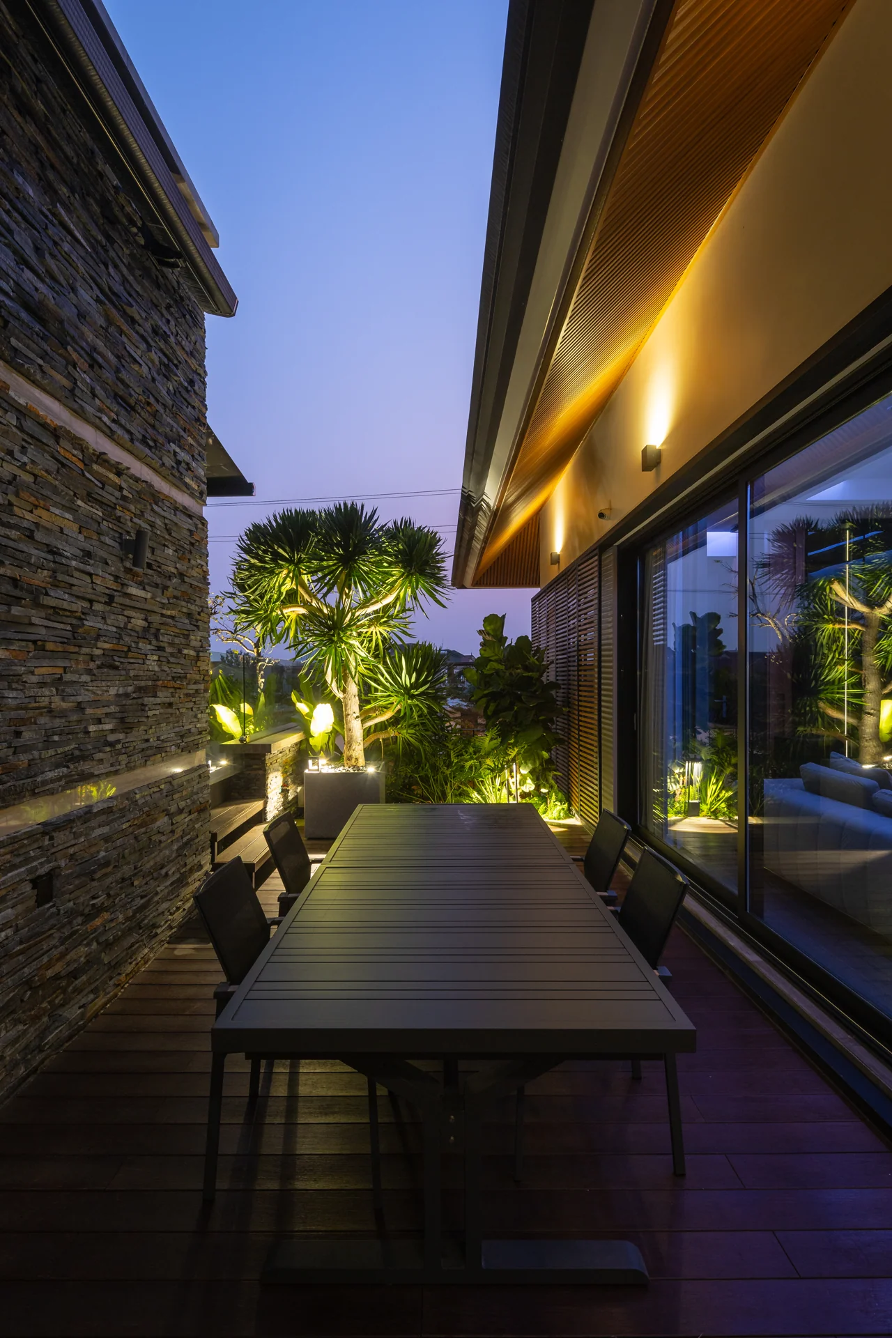 Lối đi ngoài trời giữa tường đá và cây xanh — Villa 44