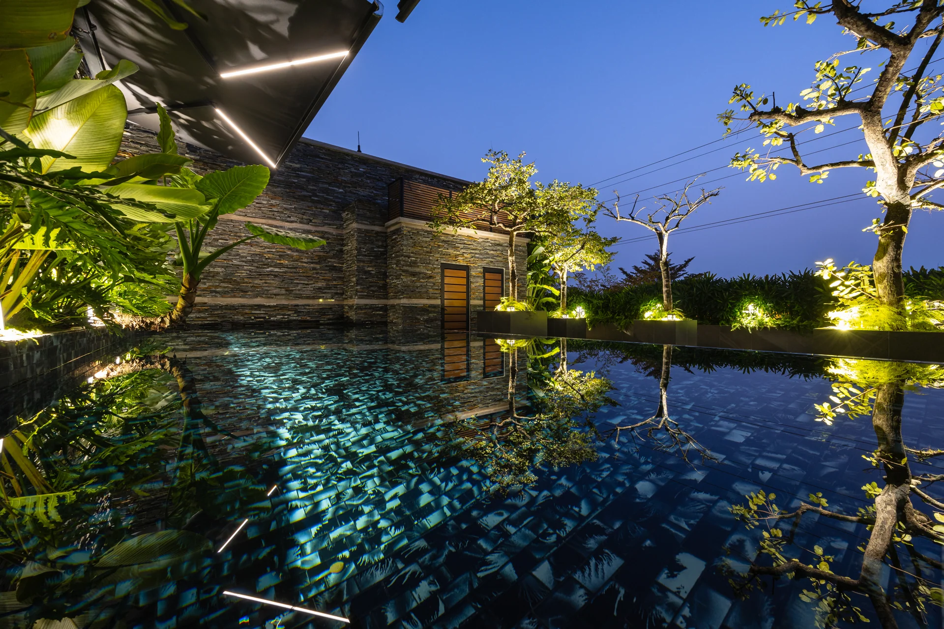 Hồ bơi và tường đá khi trời tối — Villa 44
