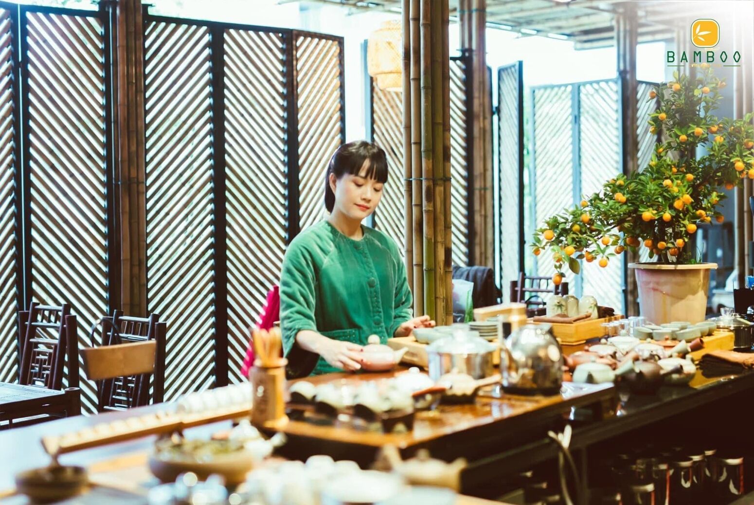Một vị khách bên bàn — ánh sáng ấm tôn không gian tre và hoa