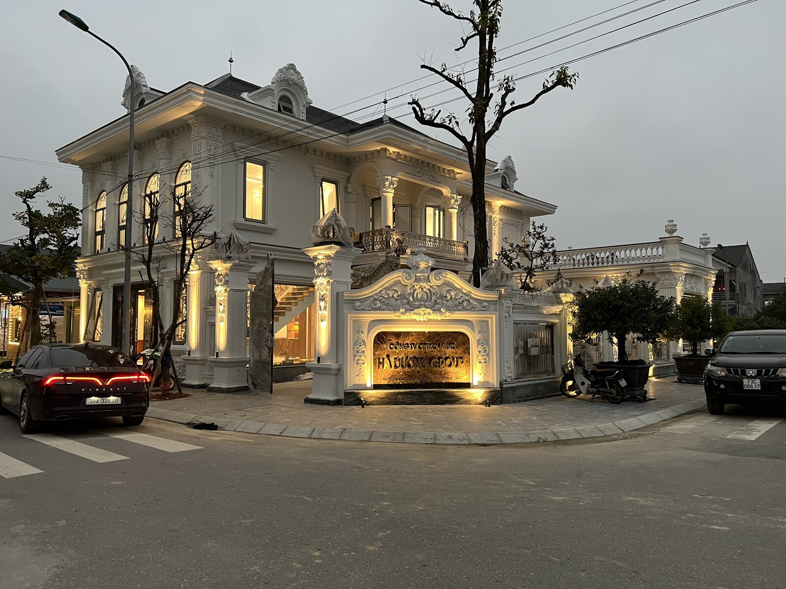 Góc nhìn nghiêng mặt tiền về đêm — ánh vàng ôm theo đường phào