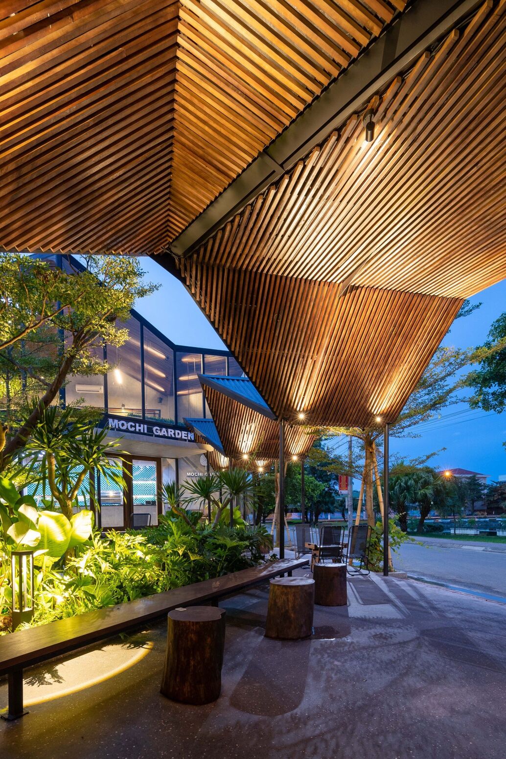 Mái pavilion nhìn từ dưới lúc chạng vạng — ánh sáng ôm theo nan gỗ