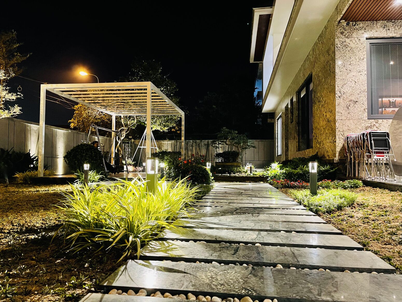 Sân vườn về đêm — pergola và cây được rọi sáng