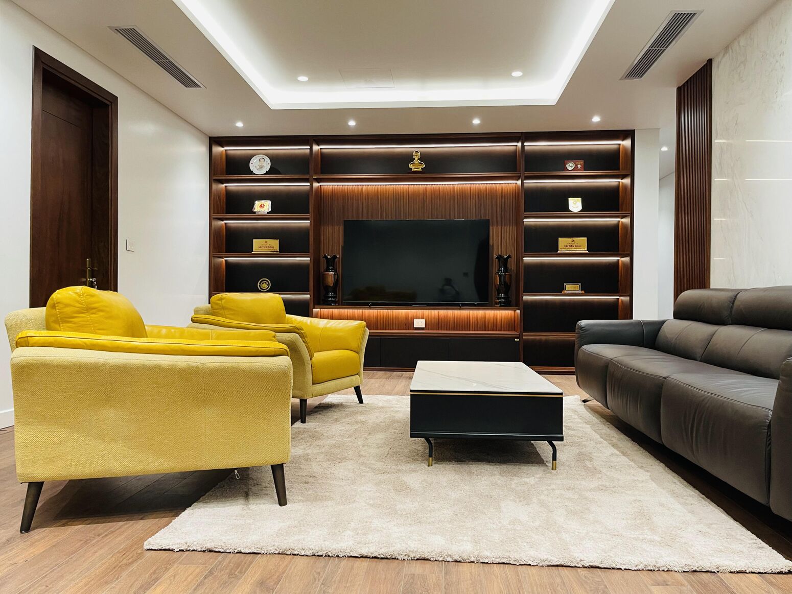 Phòng khách — sofa vàng, tường gỗ và hắt trần dịu